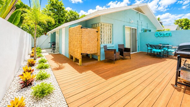 Un edificio frente al mar con una terraza de madera, asientos al aire libre y un cartel que dice 'Ocean'.