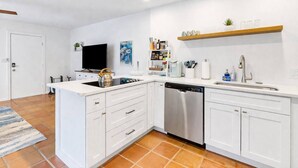 Una cocina moderna con muebles blancos, lavavajillas de acero inoxidable y horno empotrado.