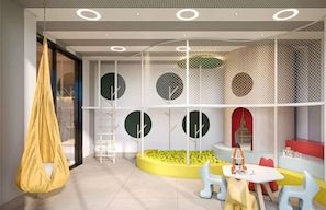 Un espace de jeux pour enfants avec un fauteuil suspendu, une petite table avec des jouets et des sièges disposés en cercle.