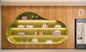 Une étagère verte et incurvée, sur laquelle sont disposés divers objets répartis sur plusieurs niveaux, le tout adossé à un mur en bois.