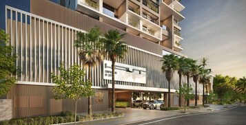 Um edifício moderno de vários andares com uma placa de destaque, ripas de madeira verticais e palmeiras.
