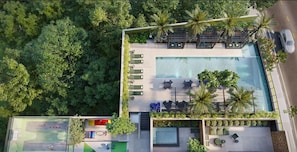 An aerial view of a resort with a swimming pool, lounge area, and a children's play area.