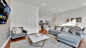Ein modernes Wohnzimmer mit einem grauen Sofa, einem Couchtisch und einem an der Wand befestigten Fernseher.
