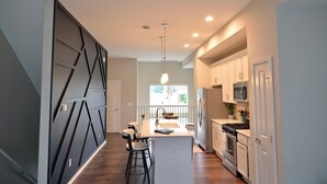 A modern kitchen with a central island, white cabinetry, and a pendant light. - Rooftop Bay Views - Downtown Lakehouse Sleeps 8 (Sandusky)