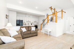 Ein modernes Wohnzimmer mit einer braunen Couch, einem weißen Couchtisch und einer Holztreppe.