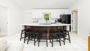 Una cucina moderna con mobili bianchi, un frigorifero nero e un'isola centrale con sgabelli da bar.