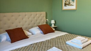 Un lit bien fait, avec une couvre-lit à motifs, deux oreillers et des serviettes pliées posées sur le côté.