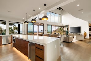 Eine moderne Küche mit einer großen Kochinsel, Holzschränken und Blick aufs Meer.