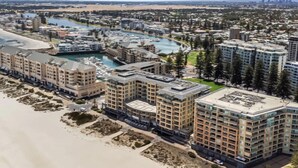 A coastal hotel with multiple buildings, a marina, and a beach. - Park View Hideaway (Glenelg)