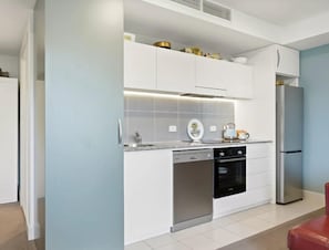 Une cuisine moderne avec des meubles blancs, un lave-vaisselle, un four et un réfrigérateur.