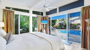 Een slaapkamer met een groot bed, een plafondventilator en een televisie.