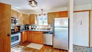 Una cocina con armarios de madera, un refrigerador de acero inoxidable, un microondas y un lavavajillas.
