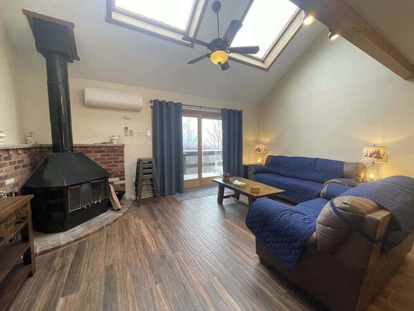 Ein gemütliches Wohnzimmer mit Kamin, Sofa, Couchtisch und einem Oberlicht.