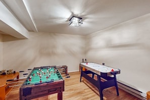 Ein Raum mit zwei Tischfußballtischen, Holzboden und einer Deckenleuchte.