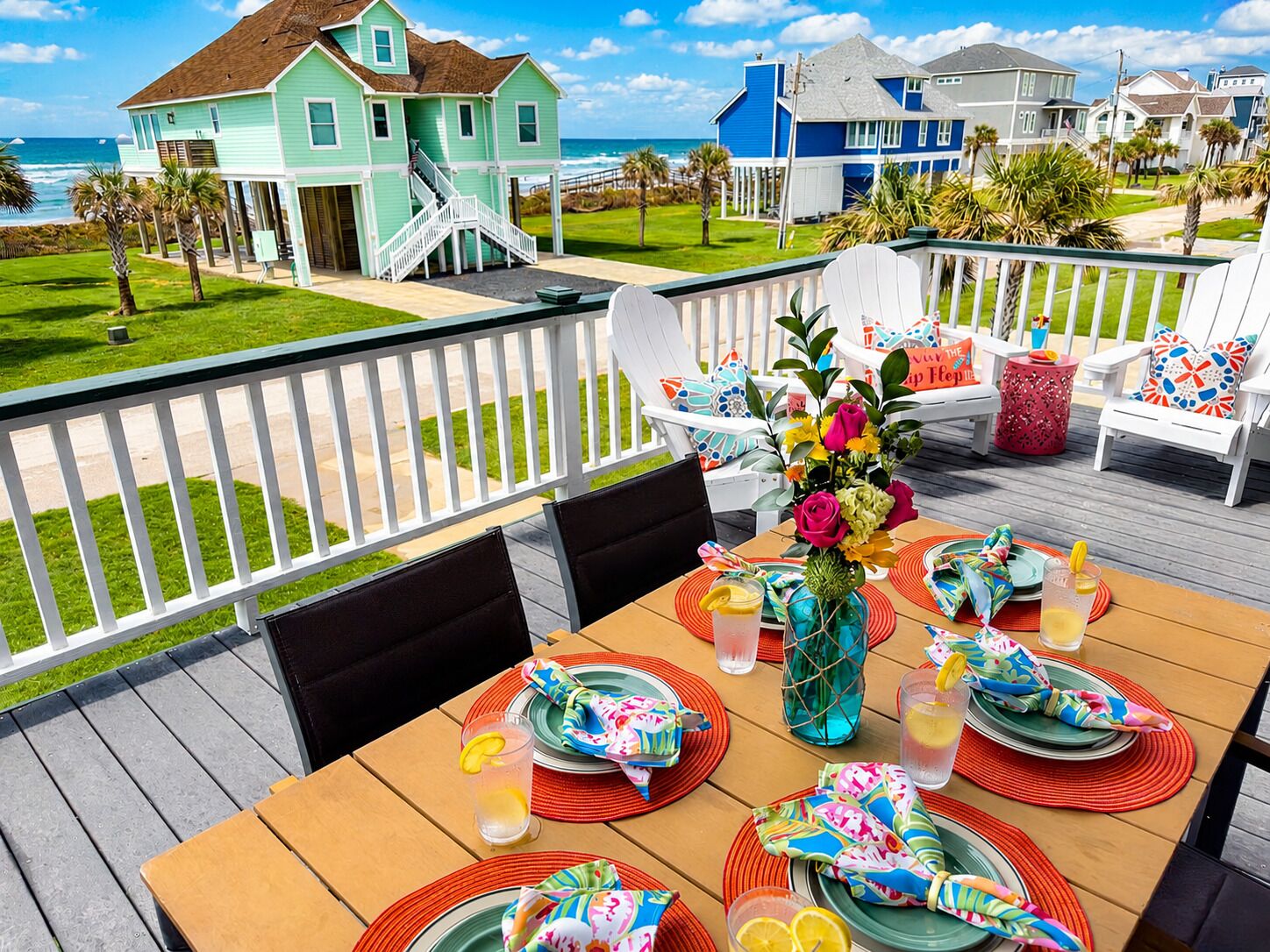 Una terraza con mesa lista para comer, con vistas a una playa y casas.