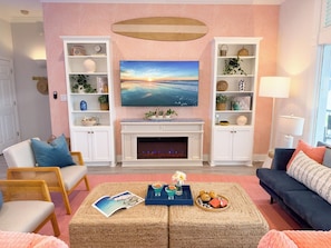 Cozy coastal living room with fireplace, built-in shelving, comfortable seating, and stylish beach-inspired décor for relaxing family stays. - 2nd Row Beach | Hot Tub & Game Room | Sleeps 16 (Galveston)