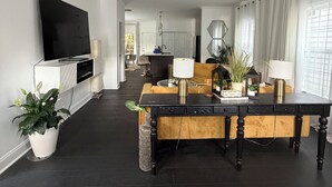 A modern living room with a flat-screen TV, a ceiling fan, a dining table with chairs, and a kitchen area in the background. - Lovely 2-bedroom house in vibrant Downtown Atlanta (Atlanta)