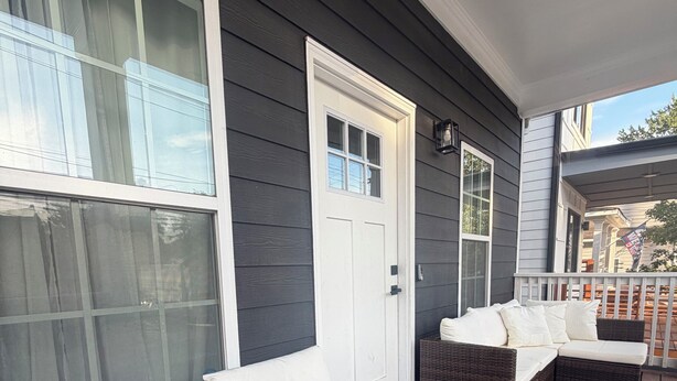 A covered porch with dark wooden flooring, white cushioned seating, and large windows. - Lovely 2-bedroom house in vibrant Downtown Atlanta (Atlanta)
