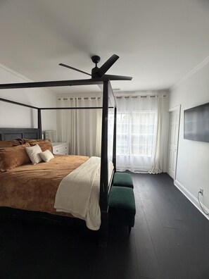 A four-poster bed with a ceiling fan, a bedside table, a green bench, and a large window with curtains. - Lovely 2-bedroom house in vibrant Downtown Atlanta (Atlanta)