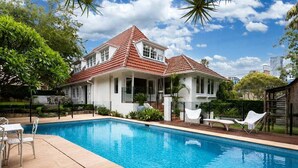 Uma casa com piscina, varanda coberta e jardim.