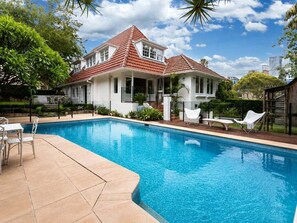 Ein Haus mit Swimmingpool, überdachter Terrasse und Garten.