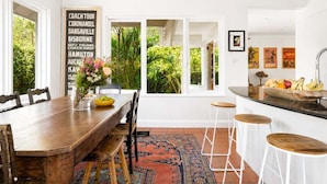 Uma sala de jantar com uma mesa de madeira, cadeiras e um espaço de bar com banquetas.