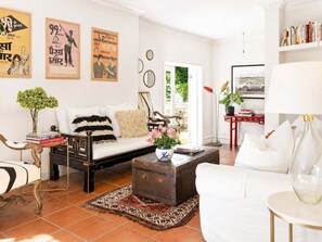 Ein Wohnzimmer mit Sofa, Couchtisch, Bücherregal und einer Tür zu einem Außenbereich.