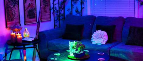 A room with a sofa, a small table with decorative items, and wall art.