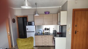 A compact kitchen with a microwave, refrigerator, and wooden cabinets. - HUGE BALCONY APARTMENT NEXT TO ONE SALONIKA OUTLET (Thessaloniki)