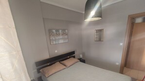 A bedroom with a bed, a nightstand, a wall-mounted lamp, and a painting. - HUGE BALCONY APARTMENT NEXT TO ONE SALONIKA OUTLET (Thessaloniki)