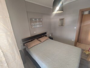 Une chambre à coucher avec un lit, une table de chevet, une lampe fixée au mur et un tableau.