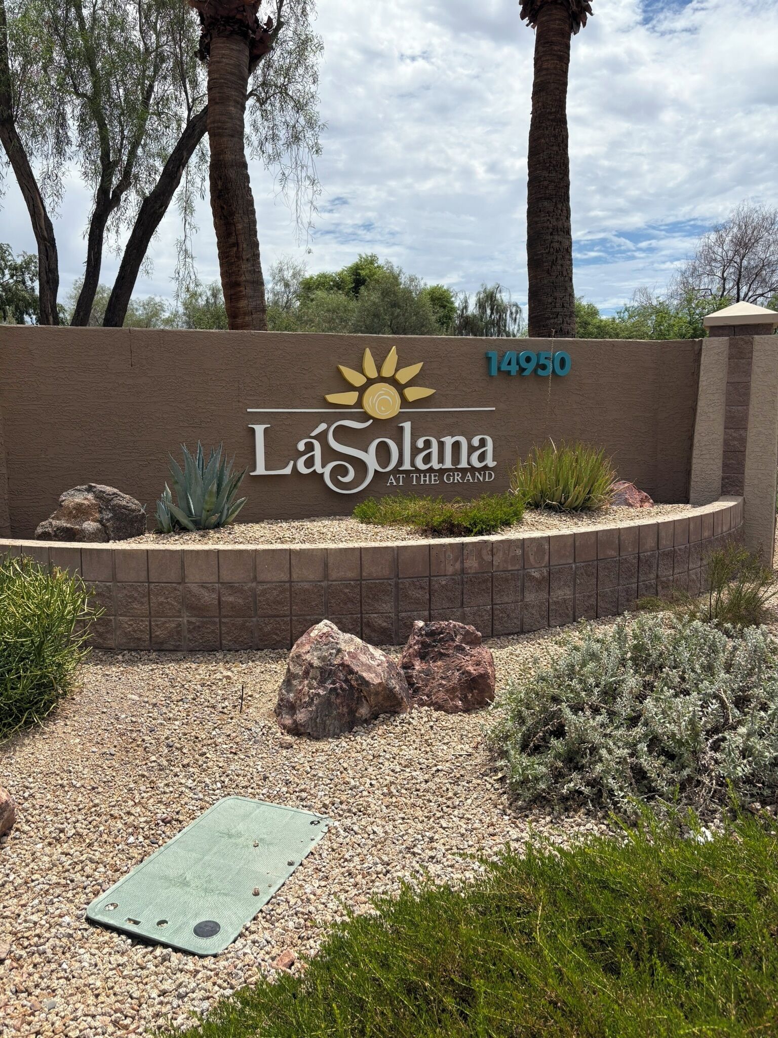 A sign for La Solana at the Grand with a number 14950, surrounded by a landscaped area with rocks and plants.