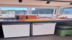 A kitchen with a window, a sink, a stove, and two refrigerators.