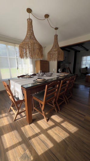 A dining area with a wooden table, chairs, and hanging wicker chandeliers.