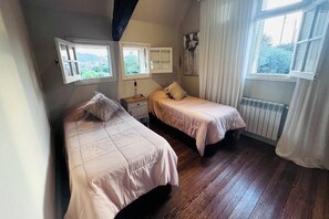 Ein Schlafzimmer mit zwei Betten, einem Fenster, einer Heizung und einem Bild an der Wand.