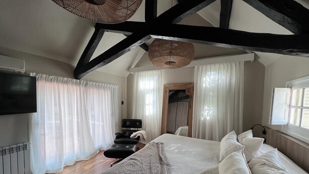 A bedroom with a large bed, a television, a chair, and a wooden door.