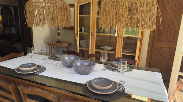 A dining table set with bowls and wine glasses, flanked by wooden chairs and a glass-top table.
