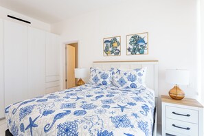 Ein Schlafzimmer mit einem Bett, Nachttischen, einem Holzkopfende und zwei Wandbildern.