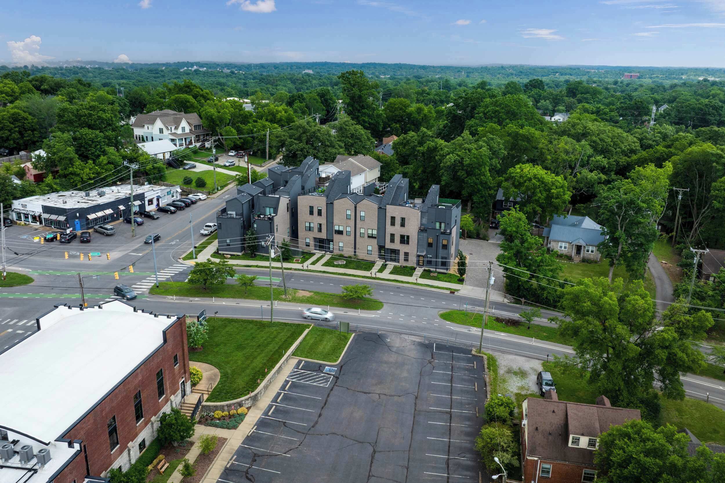 A multi-story building with a parking lot and a road intersection.