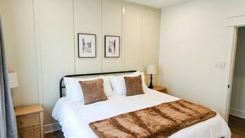 A bedroom with a bed, a nightstand, a lamp, a ceiling fan, and framed pictures on the wall.