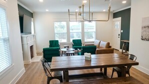 A modern kitchen with a dining area, green upholstered chairs, a wooden dining table, and a fireplace. - Cozy 3 Br Cottage, Walk to Hospitals (Tyler)