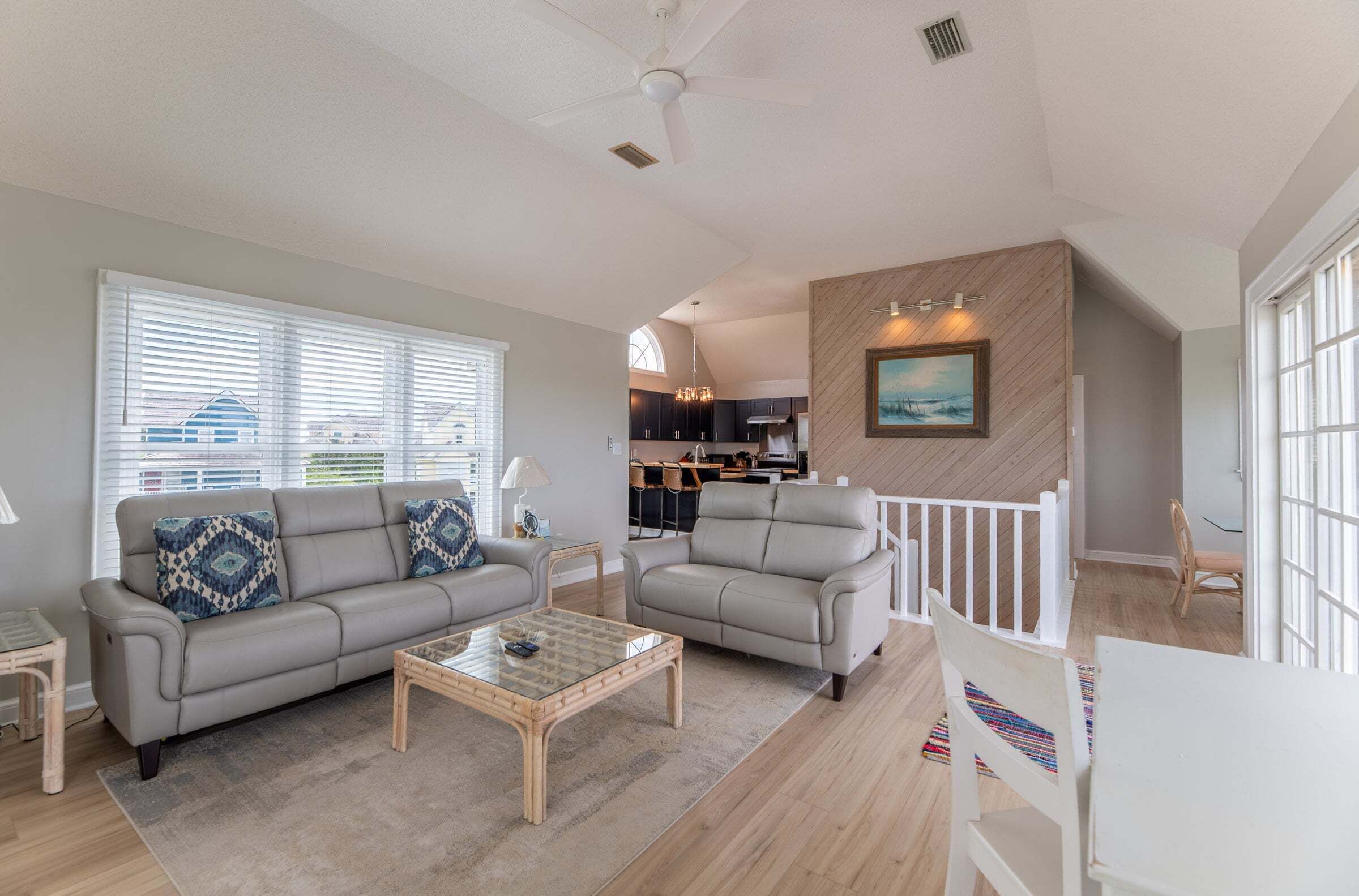 A spacious living area with a sofa, coffee table, and a view of the kitchen.