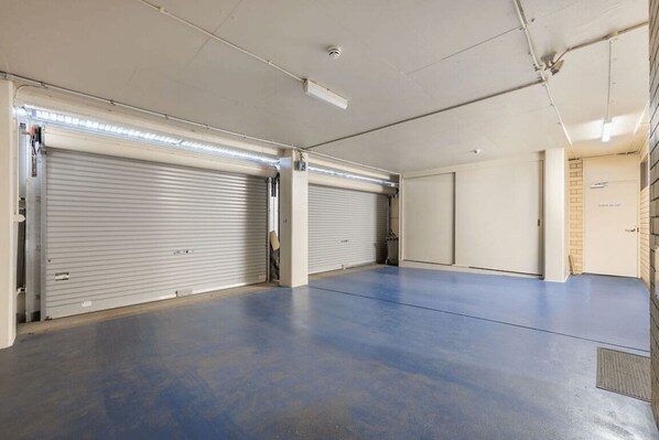 Un espacio interior amplio, con dos puertas enrollables cerradas y un piso plano y sin adornos.