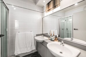 Un bany modern amb dues rentapesos, un mirall gran i una cabina de dutxa de vidre.