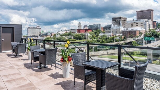 Une terrasse sur le toit avec des sièges extérieurs, un pot de fleurs et une vue sur le paysage urbain.