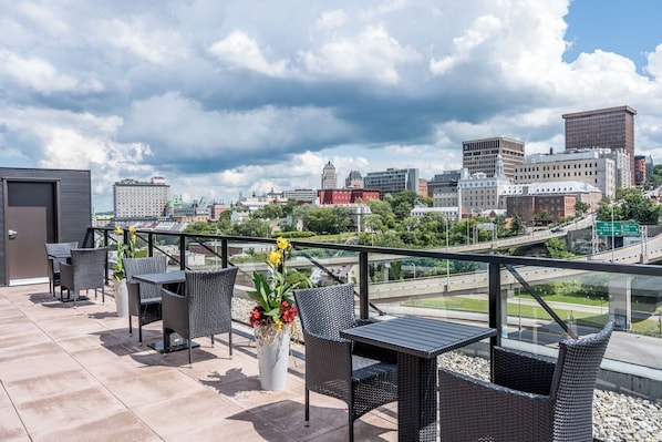 Une terrasse sur le toit avec des sièges extérieurs, un pot de fleurs et une vue sur le paysage urbain.