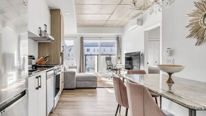 Une cuisine moderne avec un coin repas, un lustre et une grande fenêtre.