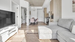 Un salon moderne avec un canapé gris, un téléviseur à écran plat et un coin repas comprenant une table et des chaises.