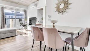 Un salon moderne avec un coin repas, de grandes fenêtres et un lustre.