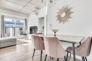 Un salon moderne avec un coin repas, de grandes fenêtres et un lustre.